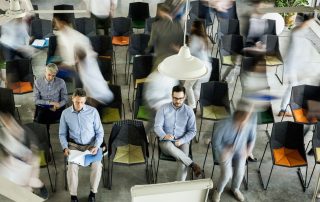 Veduta dall’alto di uomini tra i loro colleghi in movimento sfocato durante un seminario.