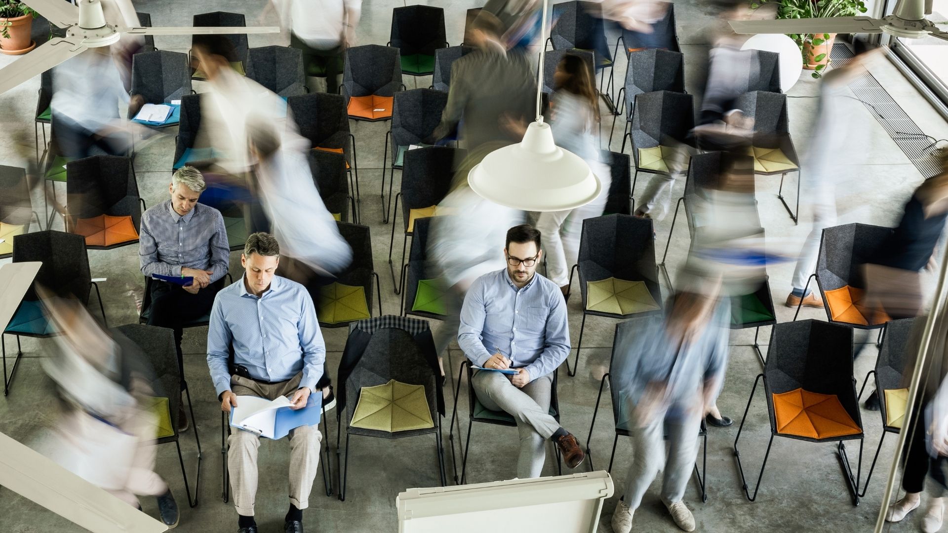 Veduta dall’alto di uomini tra i loro colleghi in movimento sfocato durante un seminario.