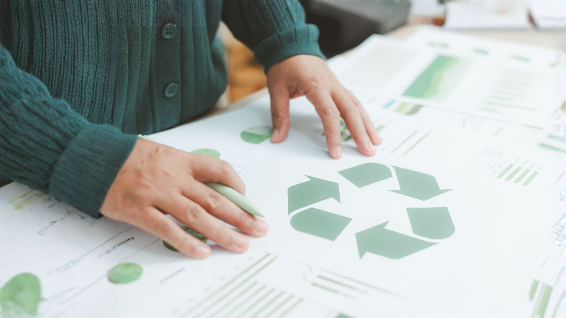 Mani appoggiate su un progetto con il simbolo verde del riciclo