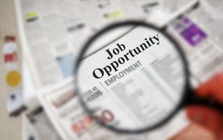Lente di ingrandimento che evidenzia un'opportunità di lavoro su un giornale