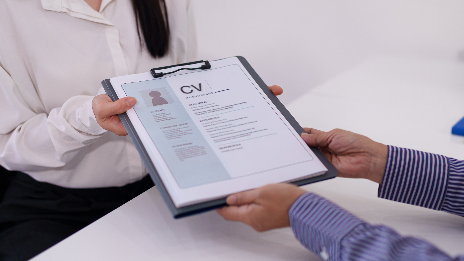 cv-efficace Close-up dello scambio di curriculum tra recruiter e discente durante un colloquio di lavoro